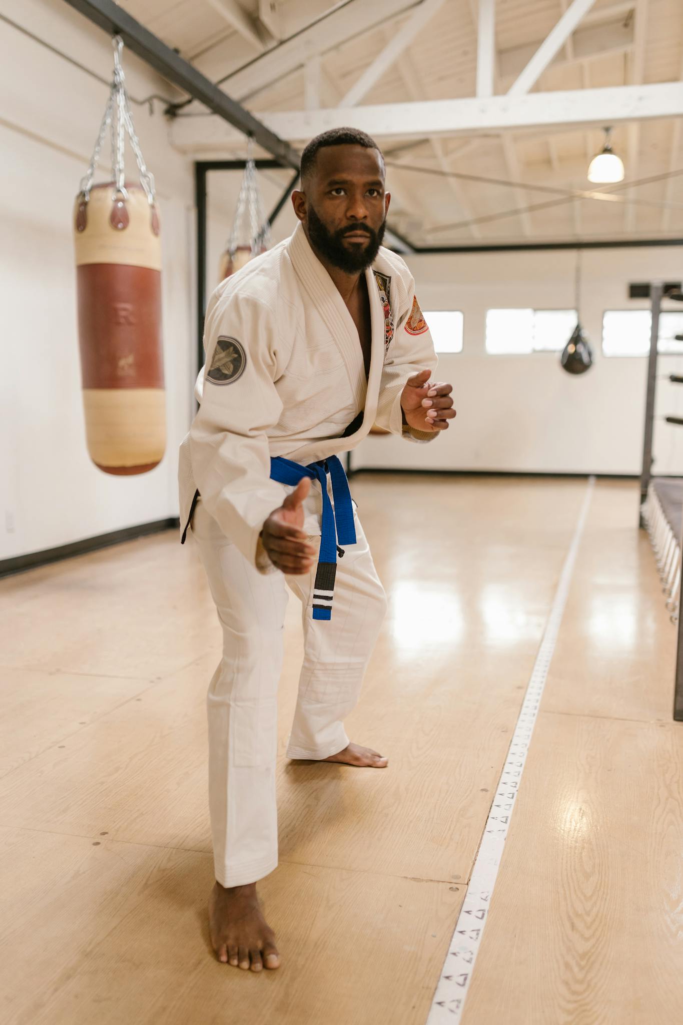 Martial artist in white gi practicing self-defense in a gym setting