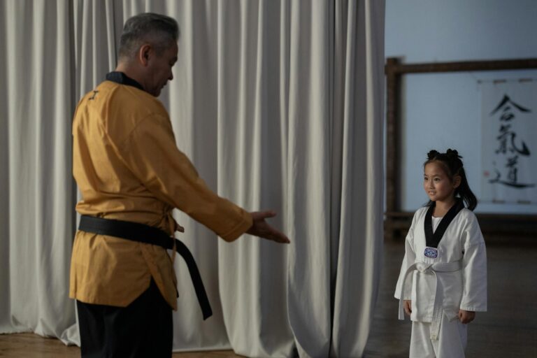 Young girl in karate gi with instructor. Martial arts training in dojo.