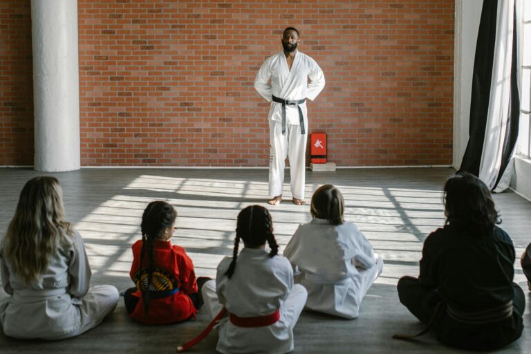 Young students in gis learn martial arts under the guidance of a black belt sensei in a dojo setting.